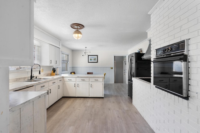 kitchen featuring sink, black appliances, white cabinets, a textured ceiling, and decorative light fixtures