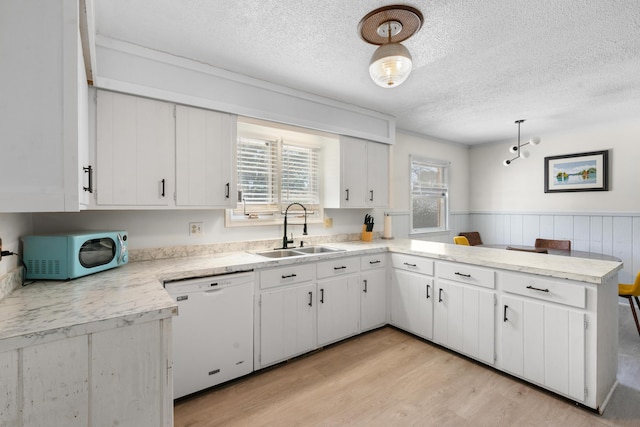 kitchen featuring white cabinetry, dishwasher, sink, and hanging light fixtures