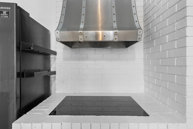 kitchen with backsplash, refrigerator, and wall chimney range hood