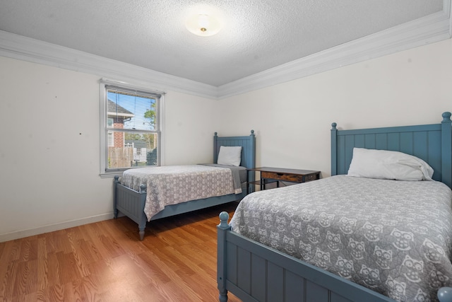 bedroom with ornamental molding, wood-type flooring, and a textured ceiling