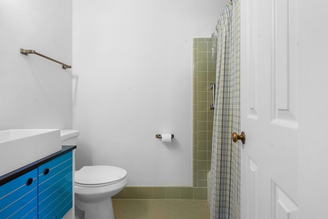 bathroom with vanity, toilet, tile patterned flooring, and a tile shower