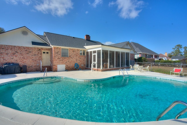 view of swimming pool with a patio area and a sunroom