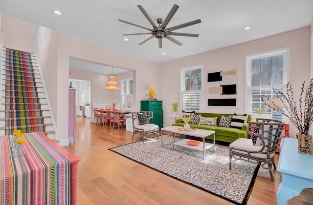 living room with light hardwood / wood-style flooring and ceiling fan with notable chandelier