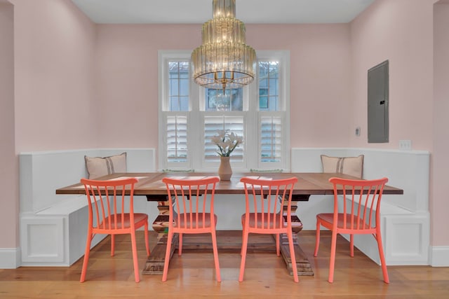 dining area with electric panel, hardwood / wood-style flooring, and an inviting chandelier