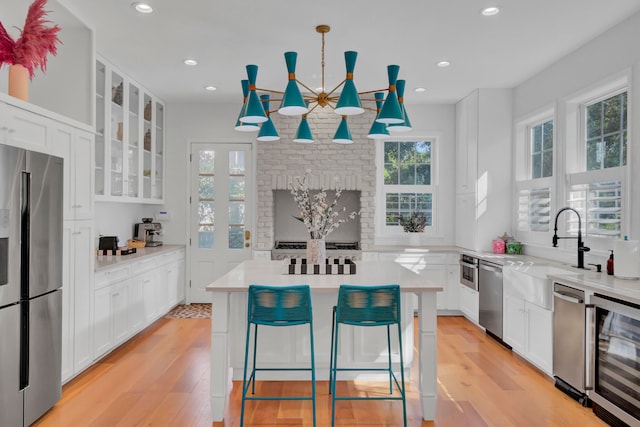 kitchen with light hardwood / wood-style floors, appliances with stainless steel finishes, decorative light fixtures, and a wealth of natural light