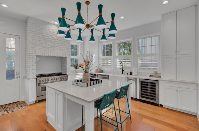 kitchen with a kitchen island, light hardwood / wood-style flooring, pendant lighting, beverage cooler, and white cabinets