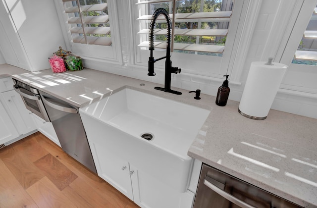 interior space with sink, white cabinets, light stone counters, and light hardwood / wood-style floors