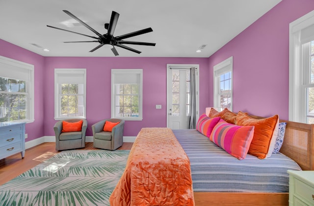 bedroom with multiple windows, access to exterior, light wood-type flooring, and ceiling fan