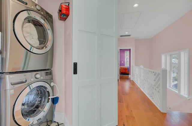 laundry room featuring stacked washer / dryer and light hardwood / wood-style flooring