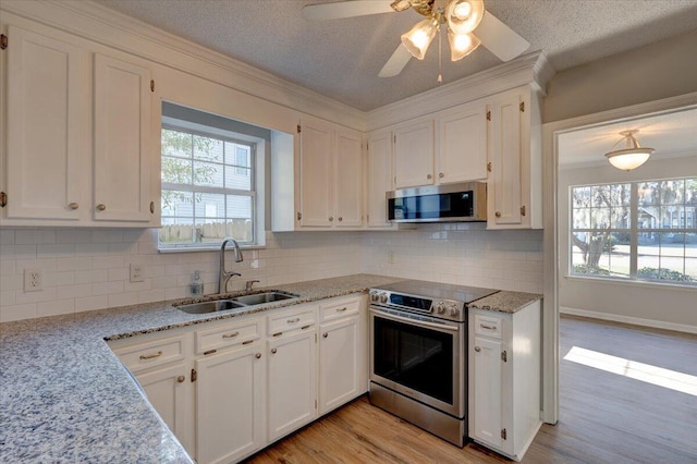 kitchen featuring white cabinets, backsplash, appliances with stainless steel finishes, and sink