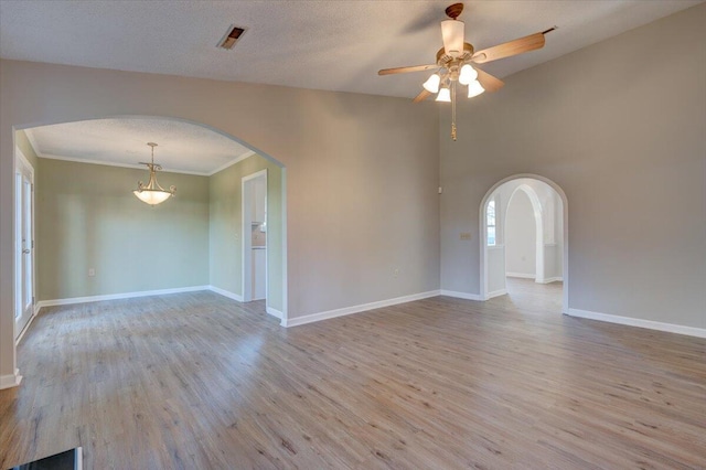 unfurnished room featuring ceiling fan, light wood-type flooring, a textured ceiling, and ornamental molding