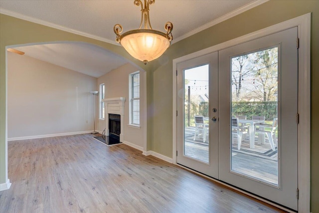 interior space with ornamental molding, french doors, and light wood-type flooring