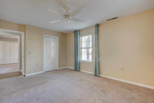 unfurnished bedroom with a textured ceiling, ceiling fan, a closet, and light carpet