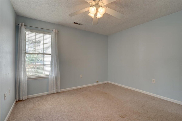 spare room with a textured ceiling, ceiling fan, and light colored carpet