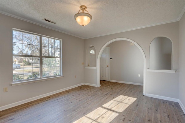 unfurnished room featuring light wood-type flooring, ornamental molding, and a textured ceiling