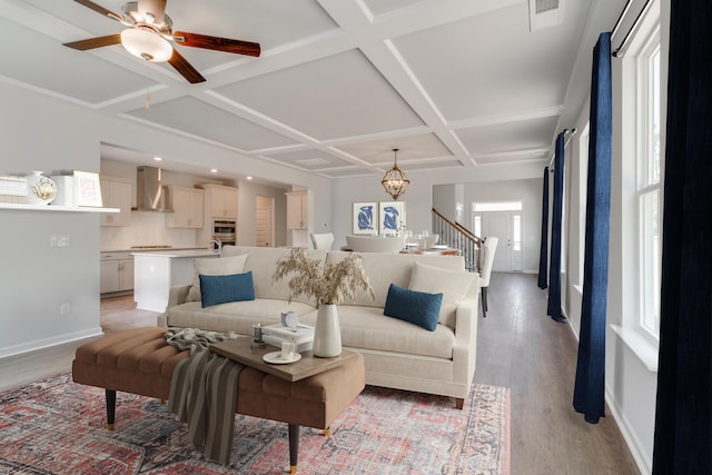 living room featuring light hardwood / wood-style floors, ceiling fan with notable chandelier, and coffered ceiling