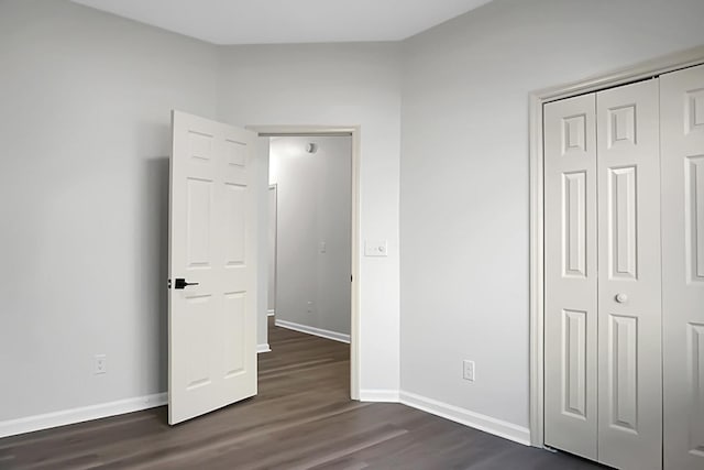 unfurnished bedroom with a closet and dark hardwood / wood-style floors