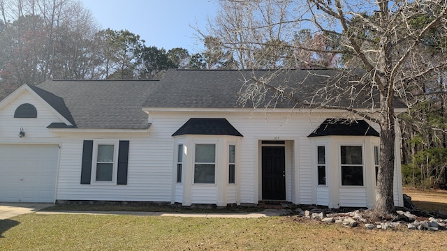 view of front of house with an attached garage, a shingled roof, and a front yard