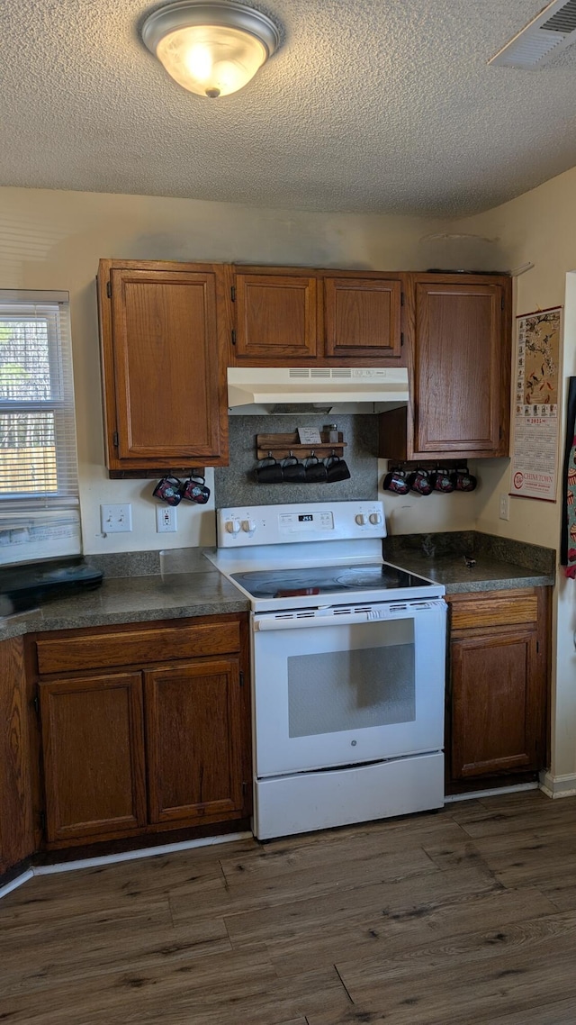 kitchen featuring dark countertops, dark wood finished floors, under cabinet range hood, and white electric range oven