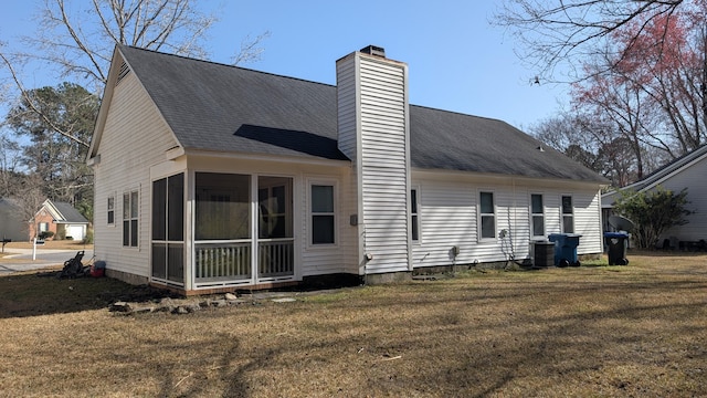 back of property with a sunroom, central AC, a yard, and a chimney