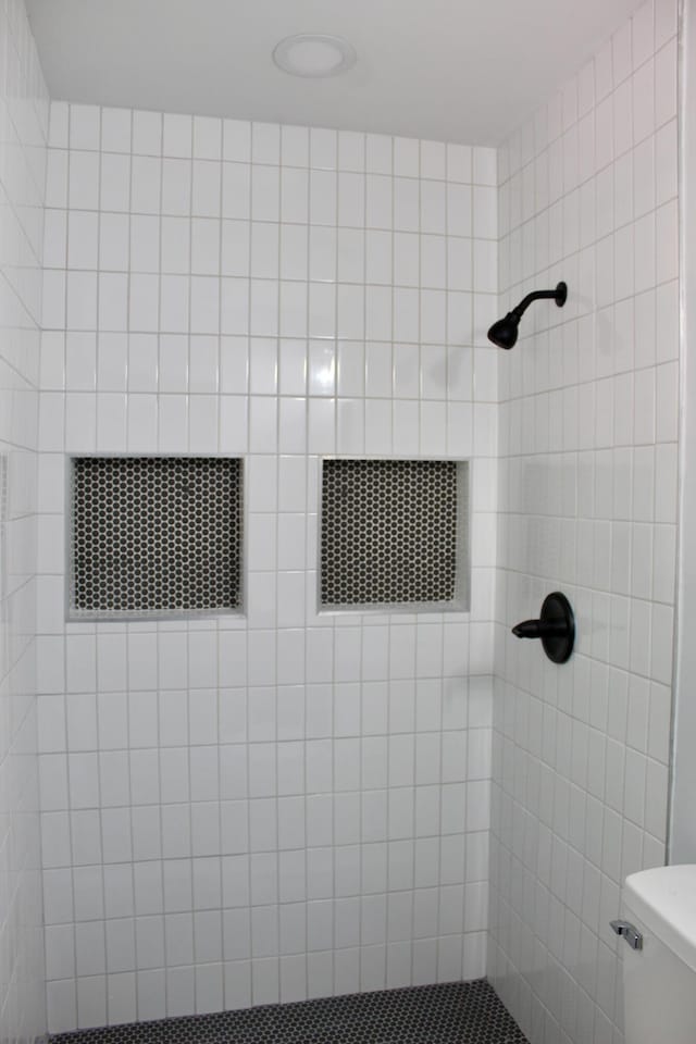 full bath featuring toilet and a tile shower