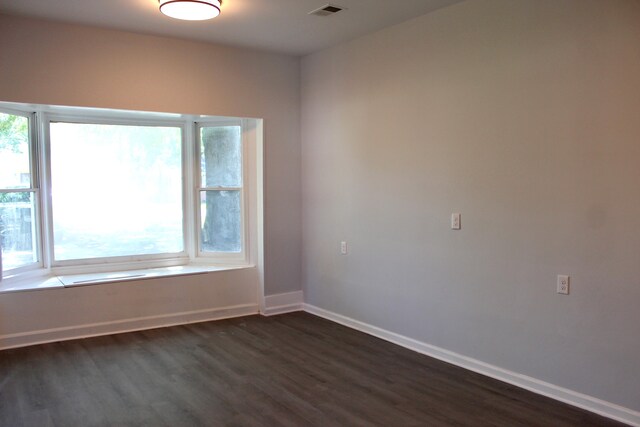spare room with baseboards, dark wood finished floors, and visible vents