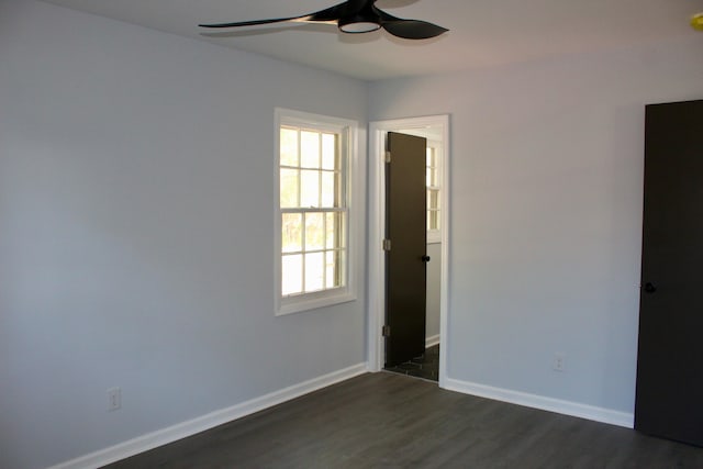 spare room with baseboards, a ceiling fan, and dark wood-style flooring