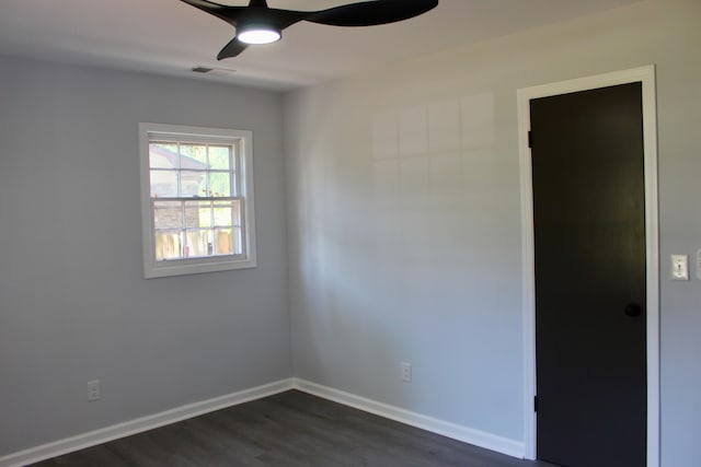 spare room featuring visible vents, a ceiling fan, baseboards, and dark wood-type flooring