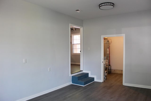 empty room featuring baseboards, dark wood finished floors, and visible vents