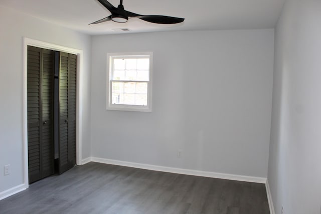 unfurnished bedroom with dark wood-style flooring, baseboards, visible vents, and a closet