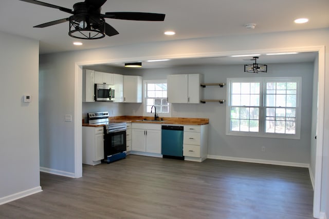 kitchen featuring a sink, butcher block countertops, stainless steel appliances, baseboards, and white cabinetry