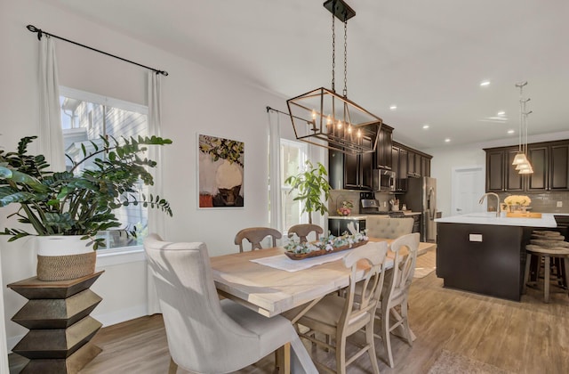 dining area featuring a notable chandelier, plenty of natural light, light wood-type flooring, and sink