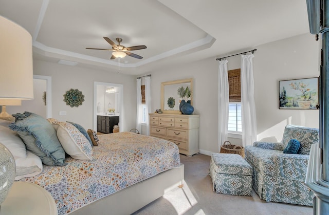 carpeted bedroom featuring ensuite bath, ceiling fan, and a tray ceiling