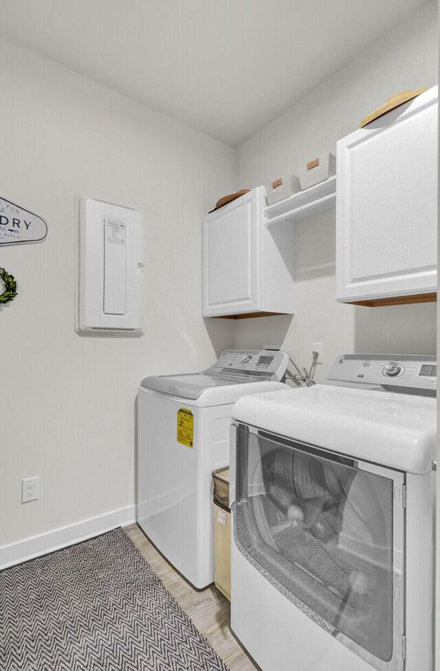 clothes washing area featuring washer and dryer and cabinets