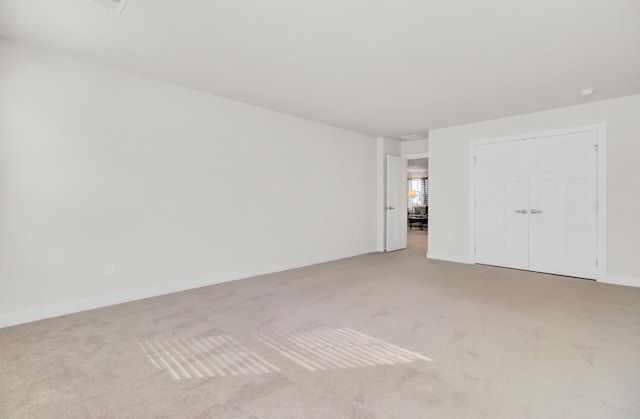 unfurnished bedroom featuring light colored carpet and a closet