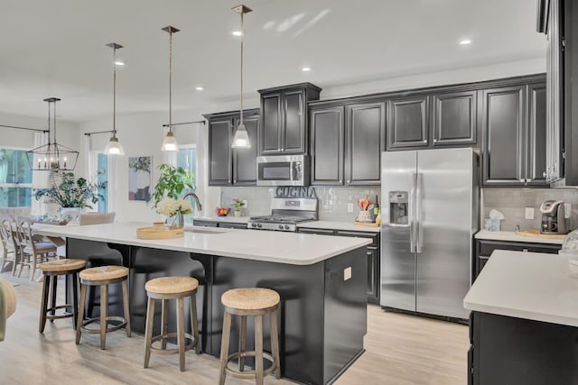 kitchen featuring sink, pendant lighting, a center island with sink, and appliances with stainless steel finishes