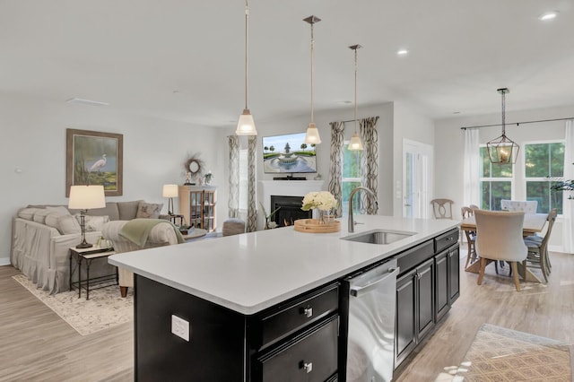 kitchen with hanging light fixtures, a kitchen island with sink, sink, and stainless steel dishwasher