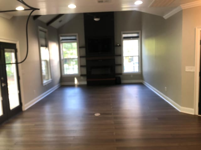 unfurnished living room featuring dark wood-style floors, baseboards, ornamental molding, and plenty of natural light