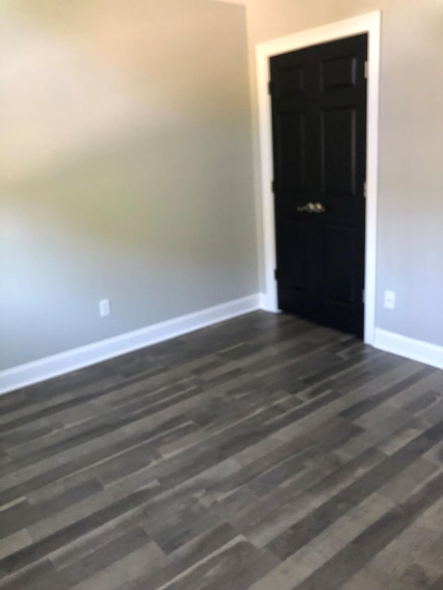 spare room featuring dark wood-style flooring and baseboards