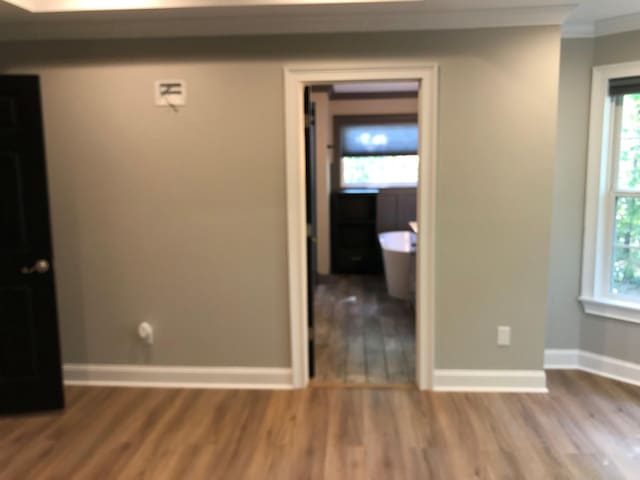 spare room with baseboards, wood finished floors, ornamental molding, and plenty of natural light