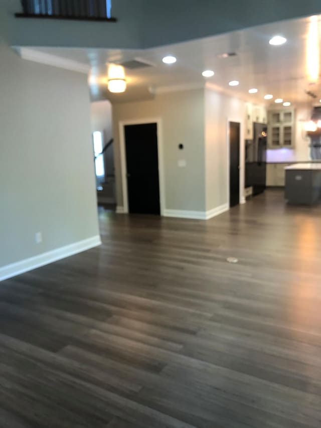 unfurnished living room featuring dark wood-type flooring, baseboards, and recessed lighting
