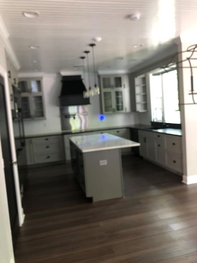 kitchen featuring a kitchen island, glass insert cabinets, dark wood-style floors, and ventilation hood