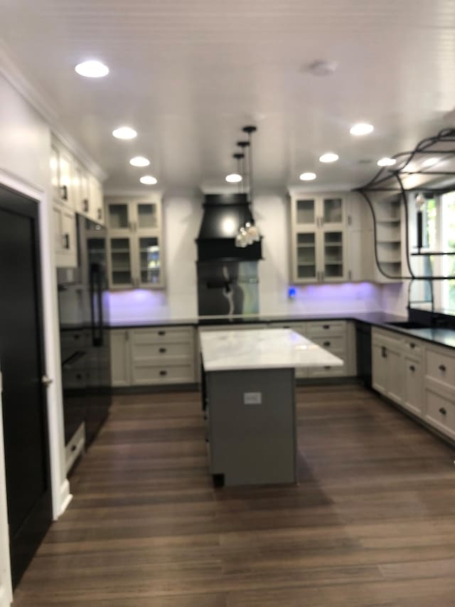 kitchen with dark wood-type flooring, freestanding refrigerator, glass insert cabinets, and range hood