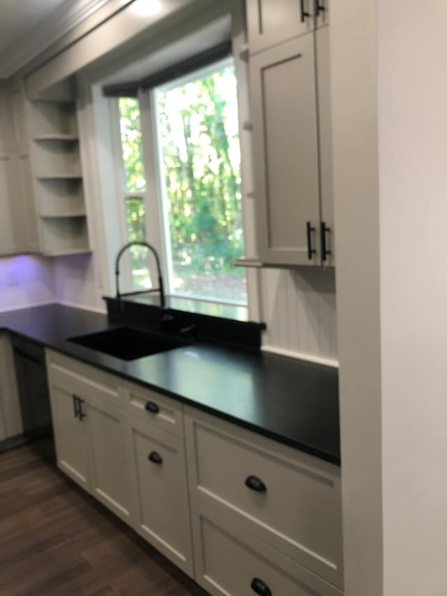 kitchen with open shelves, white cabinets, dark wood-style flooring, a sink, and dark countertops