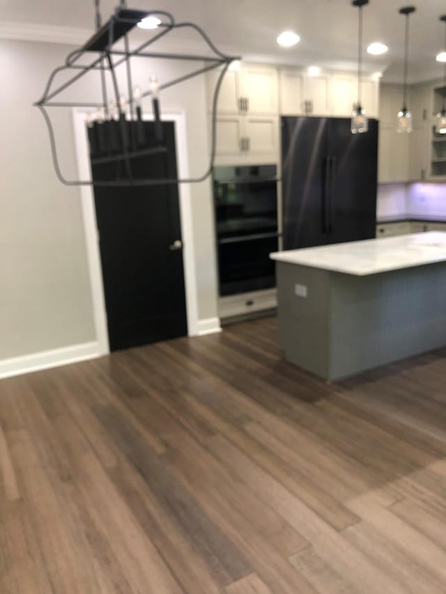 kitchen with range, decorative light fixtures, white cabinets, dark wood-style flooring, and freestanding refrigerator