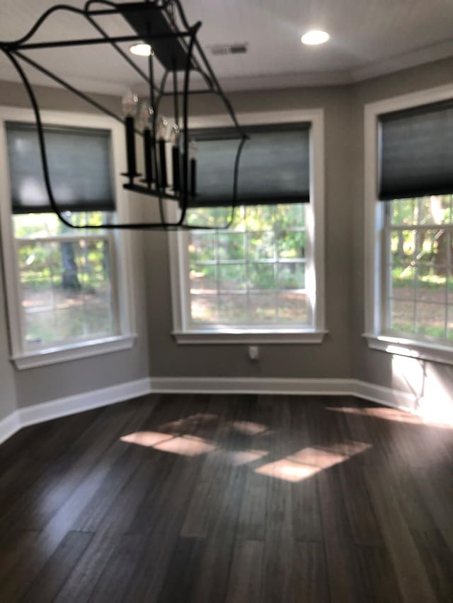unfurnished dining area with baseboards, wood finished floors, and an inviting chandelier
