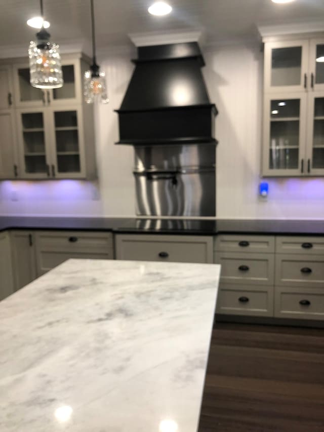 kitchen featuring custom range hood, glass insert cabinets, and ornamental molding