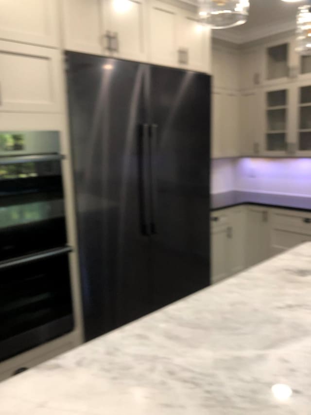 kitchen with ornamental molding, freestanding refrigerator, a chandelier, wall oven, and white cabinetry