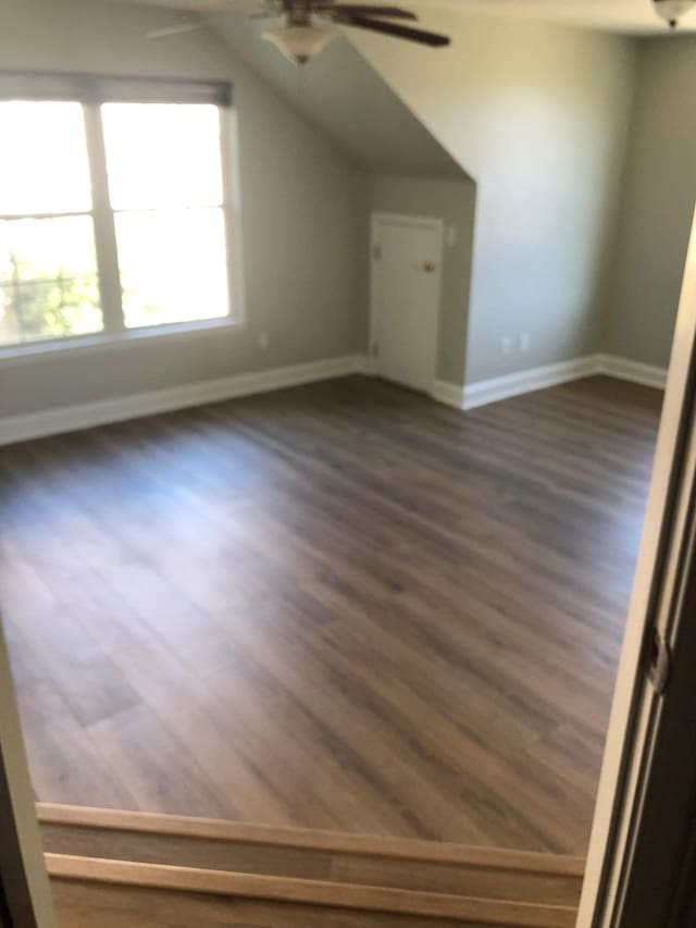 bonus room with baseboards, a ceiling fan, and dark wood-type flooring