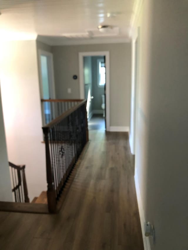 corridor featuring ornamental molding, an upstairs landing, and wood finished floors